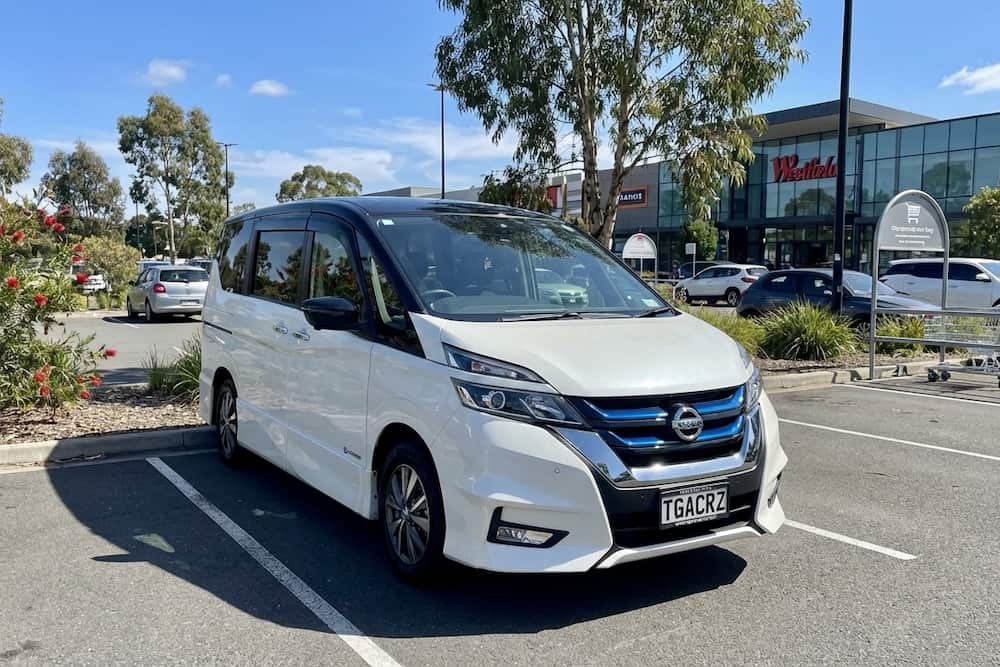 White Nissan Serena people mover parked outdoors, a practical Japanese import family van.
