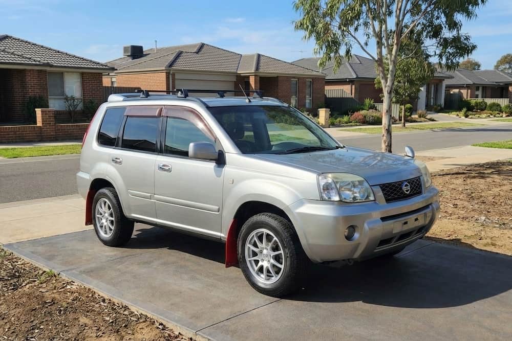Silver Nissan X-Trail GT parked in a residential driveway, a turbocharged Japanese import SUV.